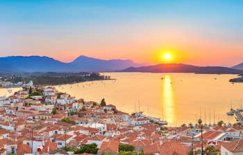 Magisk solnedgang over den farverige havneby på Poros-øen i det Ægæiske Hav, Grækenland