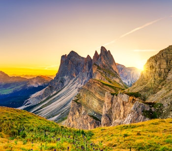 Magisk solopgang over Seceda-toppen i Dolomitterne med gyldne solstråler der oplyser det dramatiske bjerglandskab i Sydtyrol, Italien