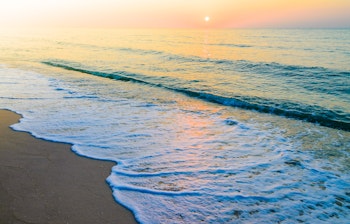 Idyllisk strandudsigt med bølger og horisont i retro vintage filter, perfekt til afslapning på sommerferien
