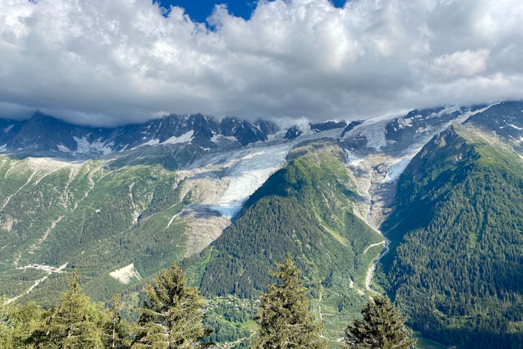 Idyllisk sommerligt alpelandskab med grønne bjerge, skov og blå himmel - perfekt til vandreferie i Alperne