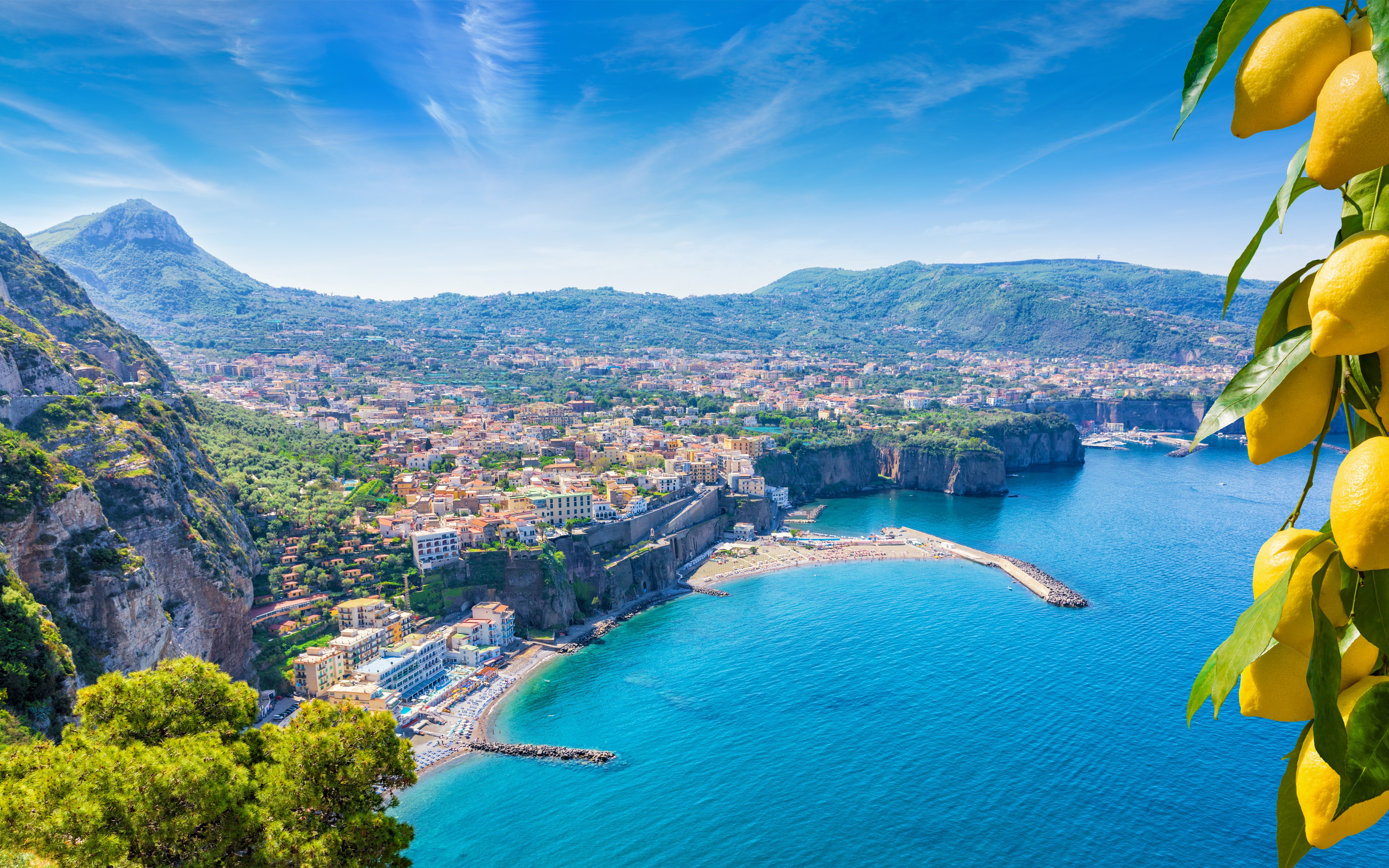 Luftfoto af Sorrentos dramatiske klippekyst med udsigt over den blå Napoli-bugt og saftige gule citroner i forgrunden, kendt for produktionen af limoncello i Italien