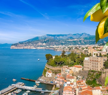 Luftfoto af Sorrentos dramatiske kystlinje med saftige gule citroner i forgrunden og udsigt over Napoli-bugten i Italien