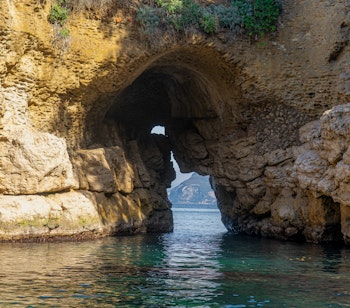 Betagende naturlig stenbue ved Regina Giovanna stranden i Sorrento, Italien, der indrammer det krystalklare turkisblå Middelhav med en smuk klippefyldt kystlinje