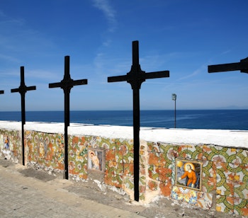 Sorte trækors på farverig keramikmur med udsigt over Middelhavet i Forio på øen Ischia, Italien, under klar blå himmel