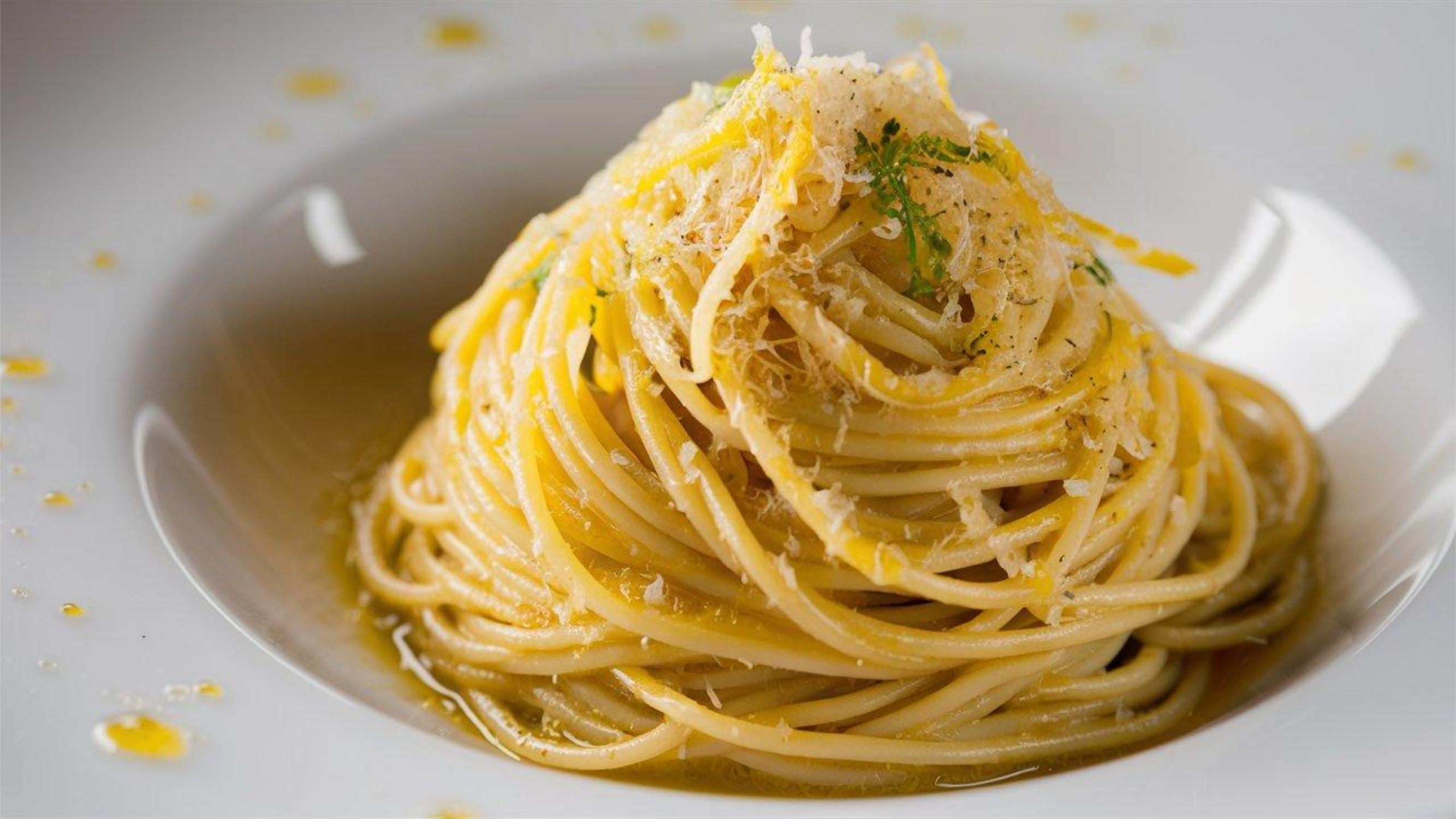 Traditionel italiensk spaghetti con bottarga med revet fiskerogn, olivenolie og citronskal serveret på hvid tallerken i Sardinien