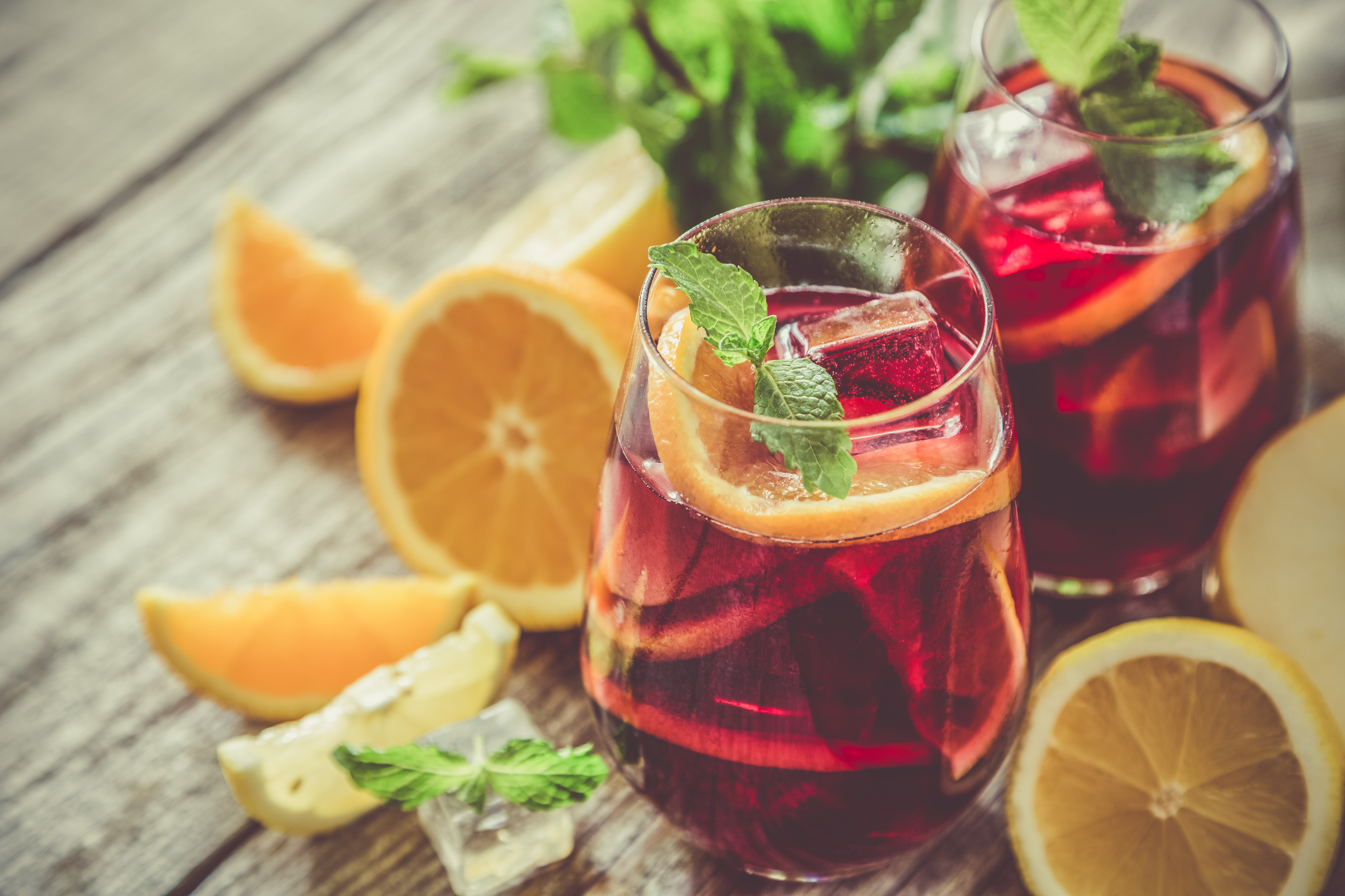 Spansk sangria cocktail med appelsinskiver og mynte på rustikt træbord