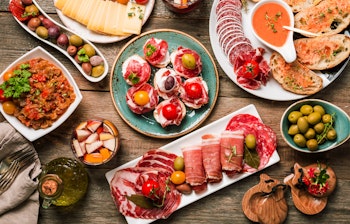 Autentisk spansk tapas-udvalg med frisk sangria serveret på rustikt træbord - en ægte smagsoplevelse fra Spaniens middelhavskøkken