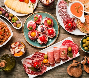 Autentisk spansk tapas-udvalg med frisk sangria serveret på rustikt træbord - en ægte smagsoplevelse fra Spaniens middelhavskøkken