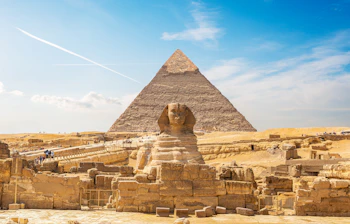 Den store Sphinx i Giza med Khafres pyramide i baggrunden under en klar blå himmel i den egyptiske ørken