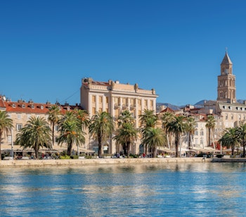 Riva-promenaden i Split med udendørs caféer, palmer og det historiske Diokletians Palads ved Adriaterhavets azurblå vand