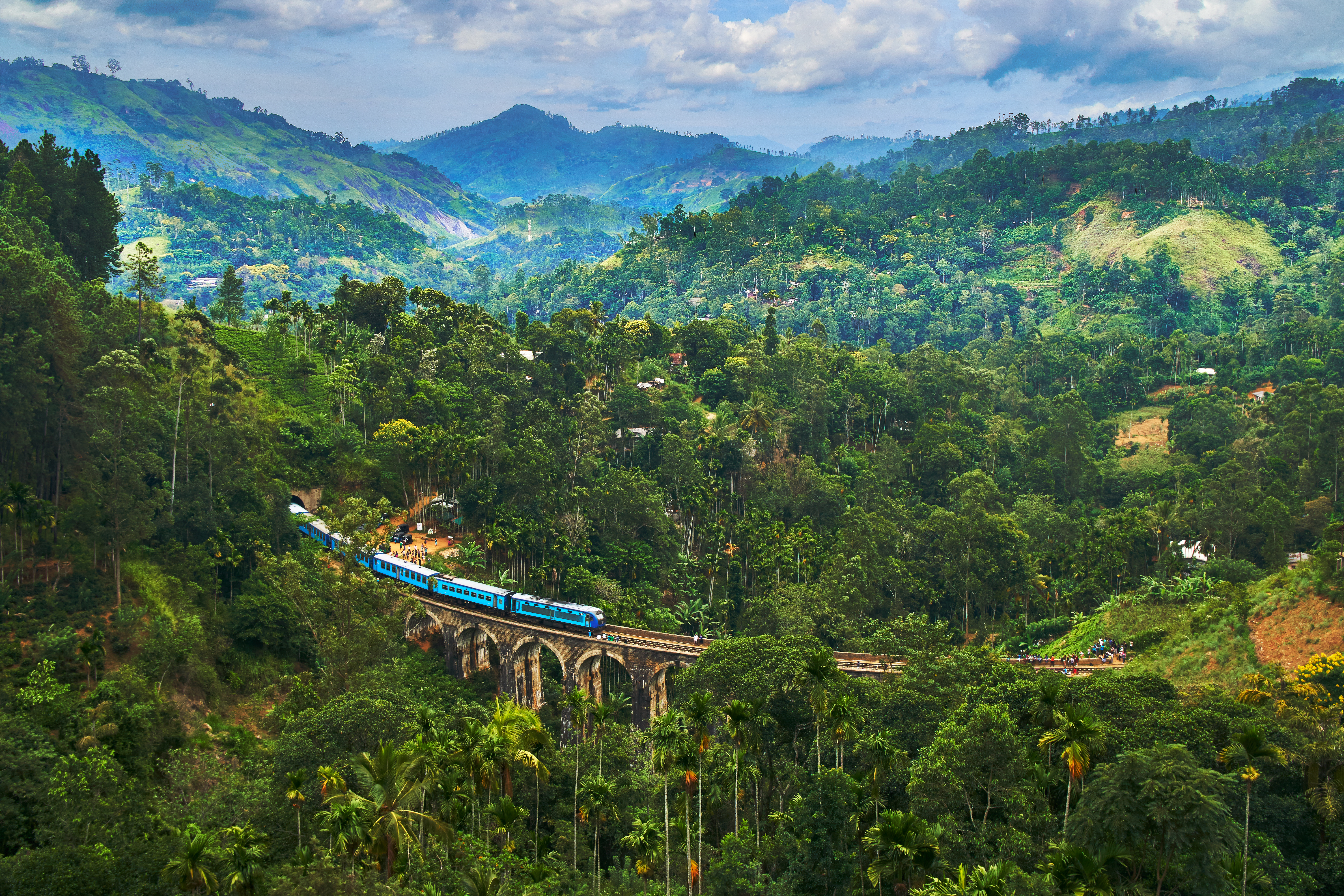 Tog krydser Nine Arches Bridge gennem frodig grøn bjerglandskab i Ella Sri Lanka