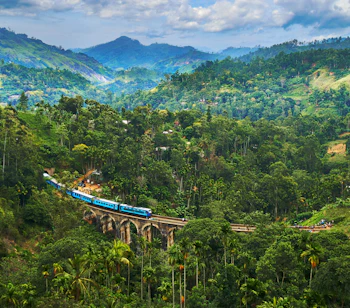 Tog krydser Nine Arches Bridge gennem frodig grøn bjerglandskab i Ella Sri Lanka
