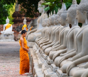 Ung stående Buddha-statue i traditionelt tempel i Thailand - symbol på buddhismens spirituelle kultur og fredfyldte ånd