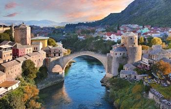 Den historiske Stari Most bro oplyst ved solnedgang over Neretva-floden i Mostar, Bosnien-Hercegovina