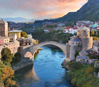 Den historiske Stari Most bro oplyst ved solnedgang over Neretva-floden i Mostar, Bosnien-Hercegovina