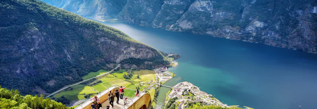 Turister på den ikoniske Stegastein udsigtsplatform med spektakulær udsigt over Aurlandsfjorden og de norske fjelde