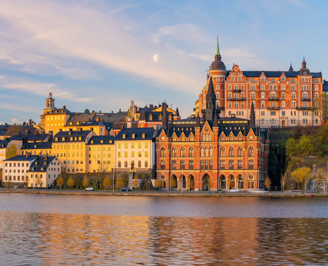 Stockholms gamle bydel Gamla Stan med farverige bygninger og historisk arkitektur badet i gyldent solnedgangslys over vandet