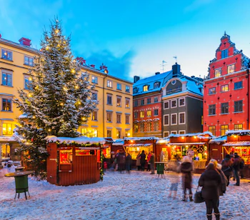 Eventyrligt julemarked med oplyste boder og snedækkede omgivelser på Stortorget i Gamla Stan, Stockholm