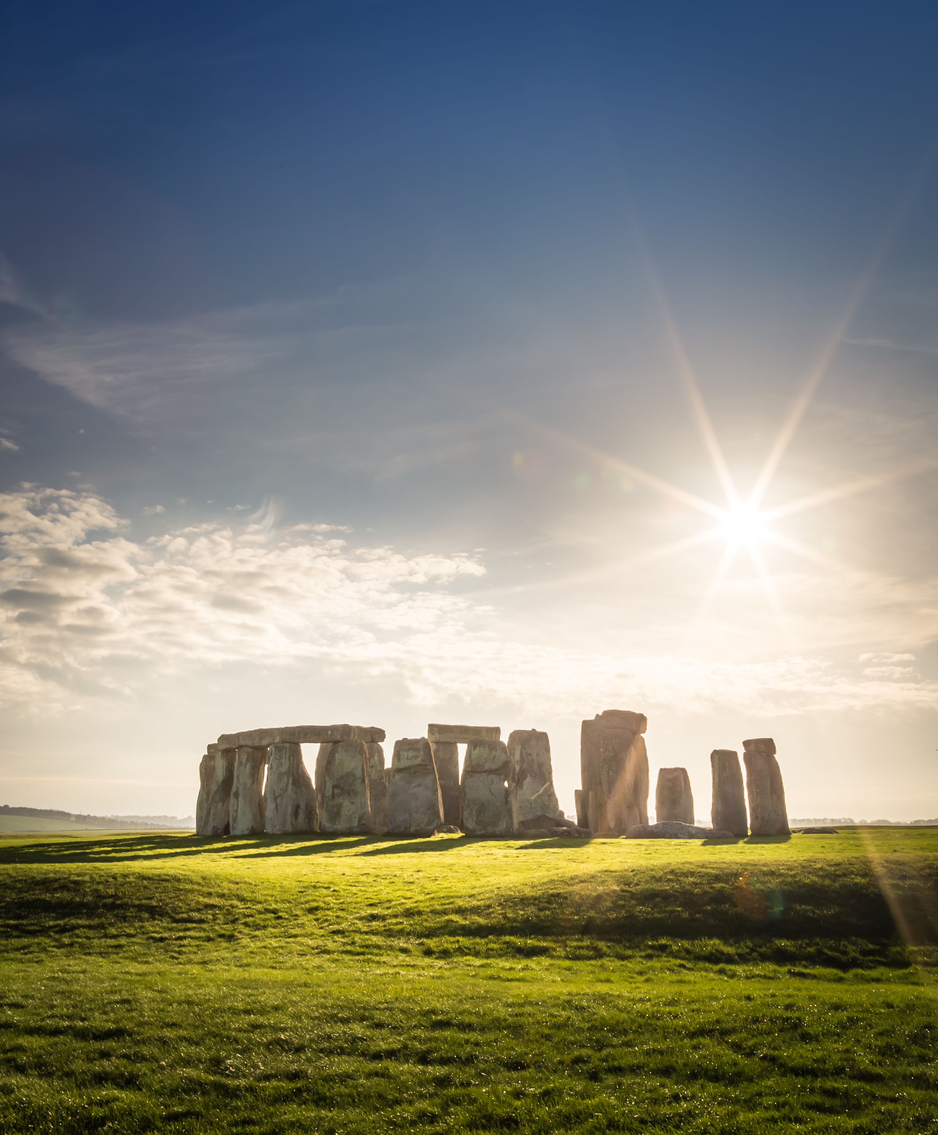 Det berømte Stonehenge stenmonment i England med solstråler og grønt landskab