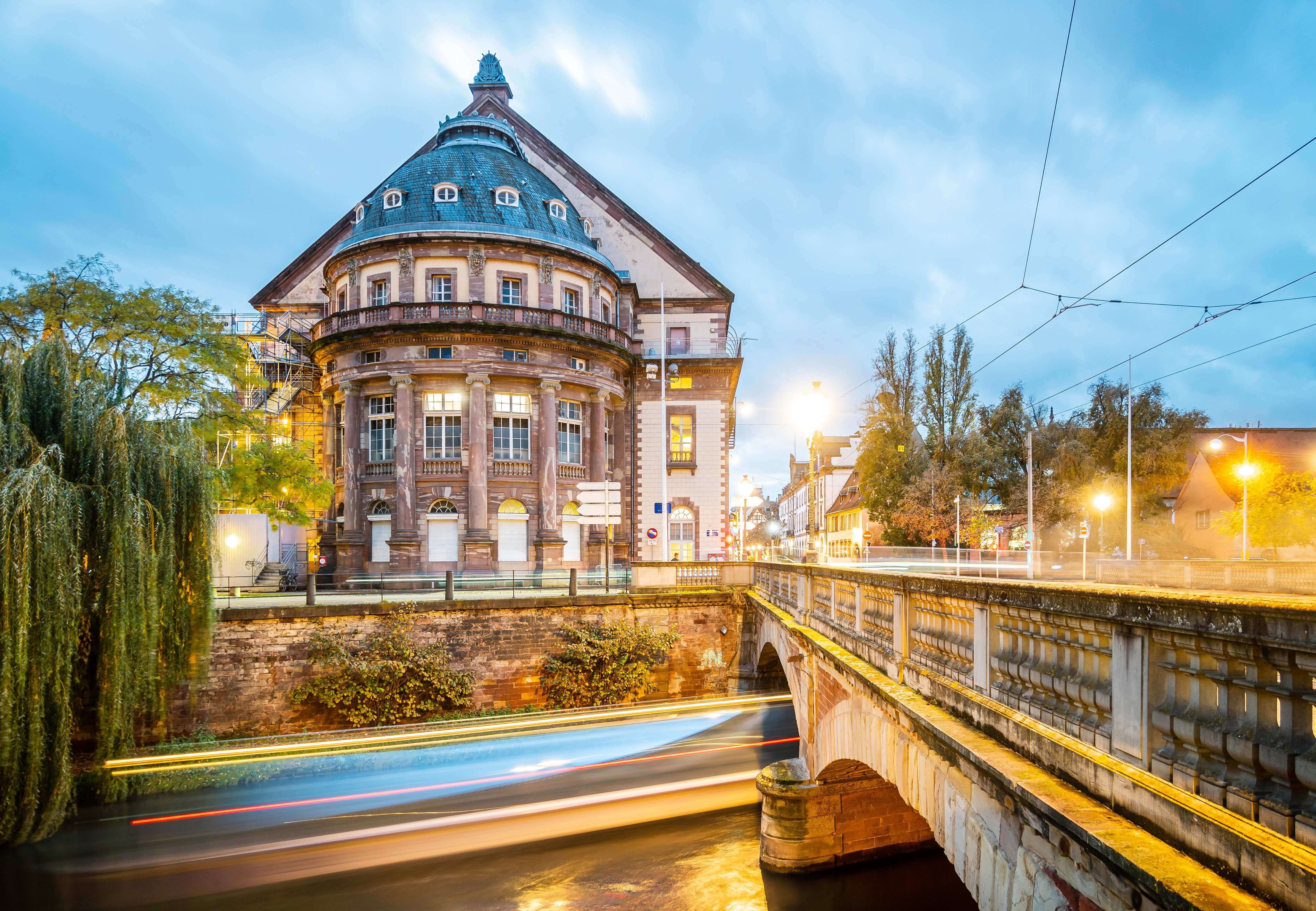 Strasbourgs smukke operahus oplyst i aftenlys med lysrefleksioner i Rhinfloden, set fra Teaterbroen i Alsace, Frankrig