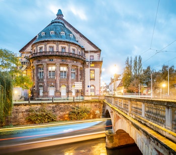 Strasbourgs smukke operahus oplyst i aftenlys med lysrefleksioner i Rhinfloden, set fra Teaterbroen i Alsace, Frankrig