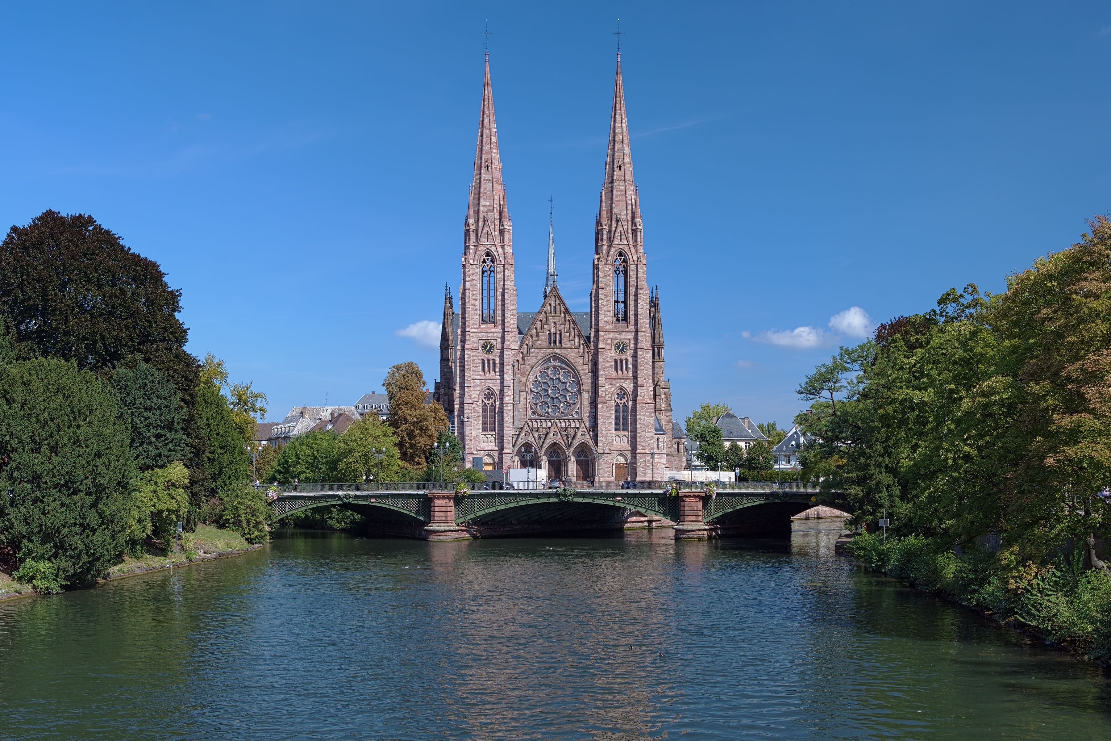 Den historiske Saint-Paul kirke med sine gotiske tårne spejler sig i Ill-floden i Strasbourg, et smukt eksempel på Alsace-regionens arkitektur