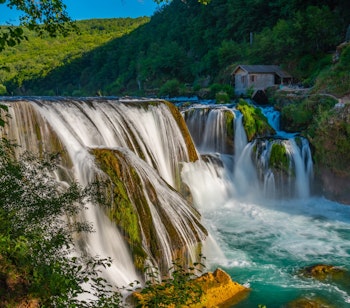 Det smukke Strbacki Buk vandfald i Una Nationalpark, Bosnien-Hercegovina, med krystalklart vand der falder gennem den frodige grønne skov
