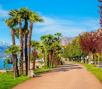 Idyllisk offentlig park ved promenaden i Stresa med udsigt over Lago Maggiore-søen og de italienske alper