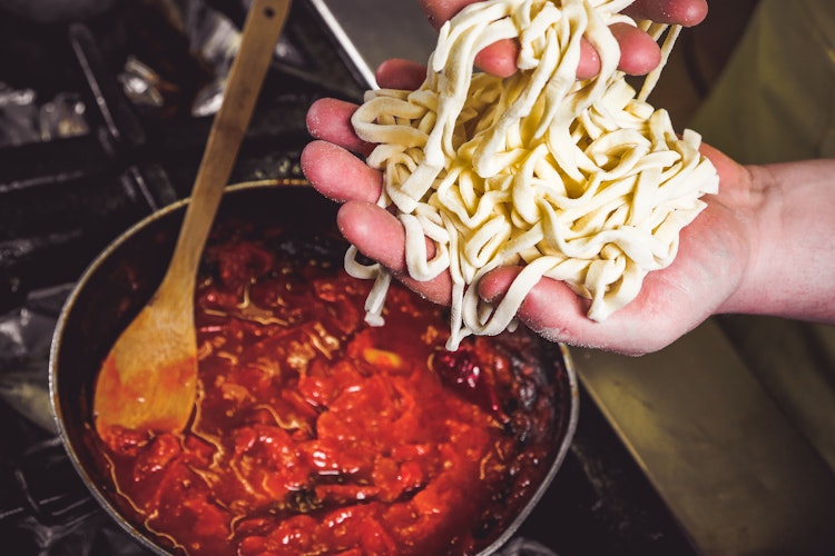 Traditionel stringozzi pasta fra Umbrien tilberedes med tomat og hvidløg under madlavningskurset på vores hotel i Trevi - en smagfuld oplevelse på elcykelrejsen gennem Italien