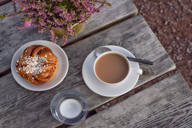 Traditionel svensk fika med kanelbolle og kaffe på rustikt træbord