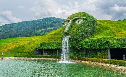 Den ikoniske fontæne med et kæmpestort grønt hoved, der spytter vand ved indgangen til Swarovski Kristallwelten i Wattens, Østrig
