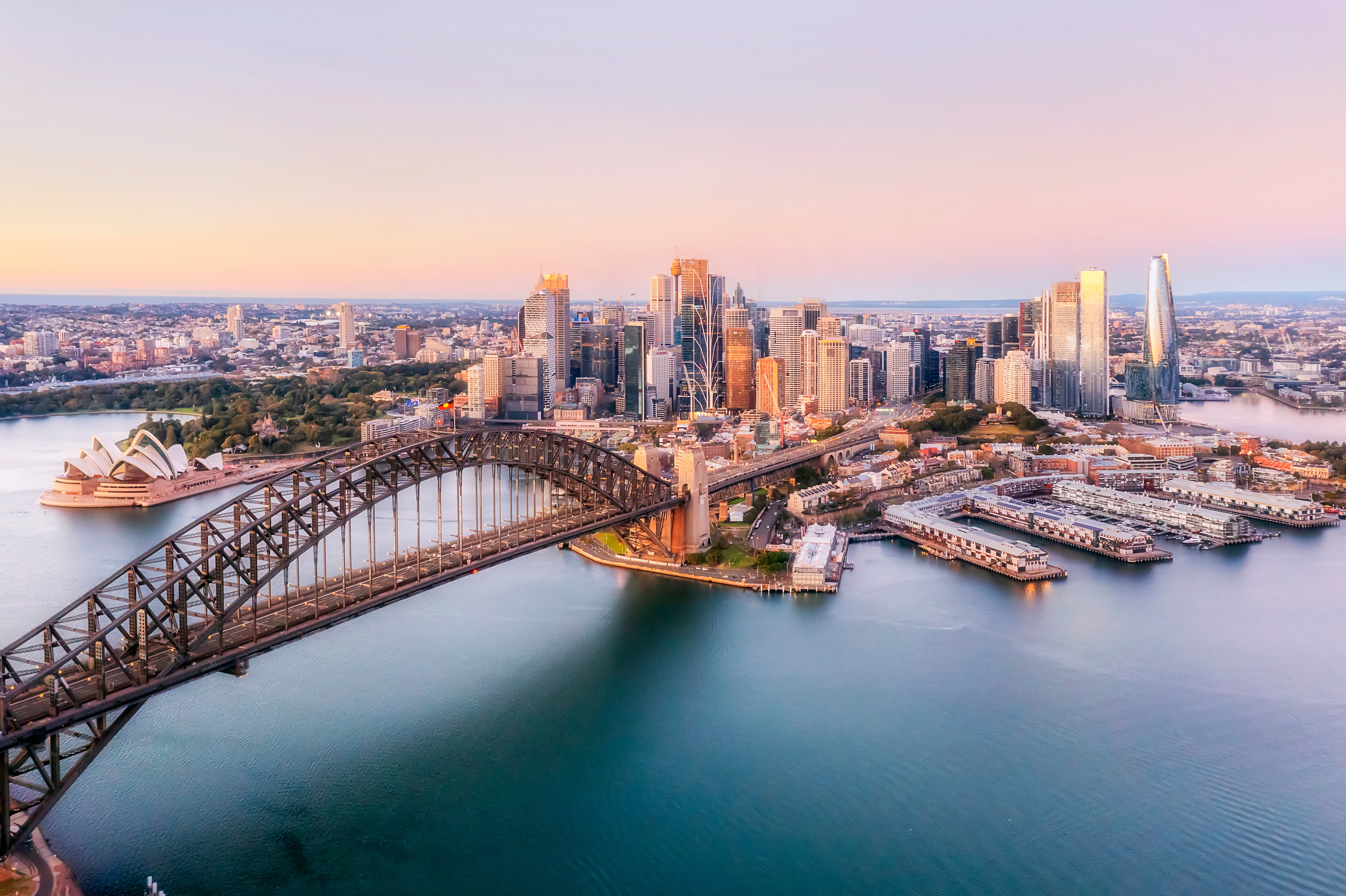 Sydney Harbour Bridge og Opera House ved solnedgang med byens skyline