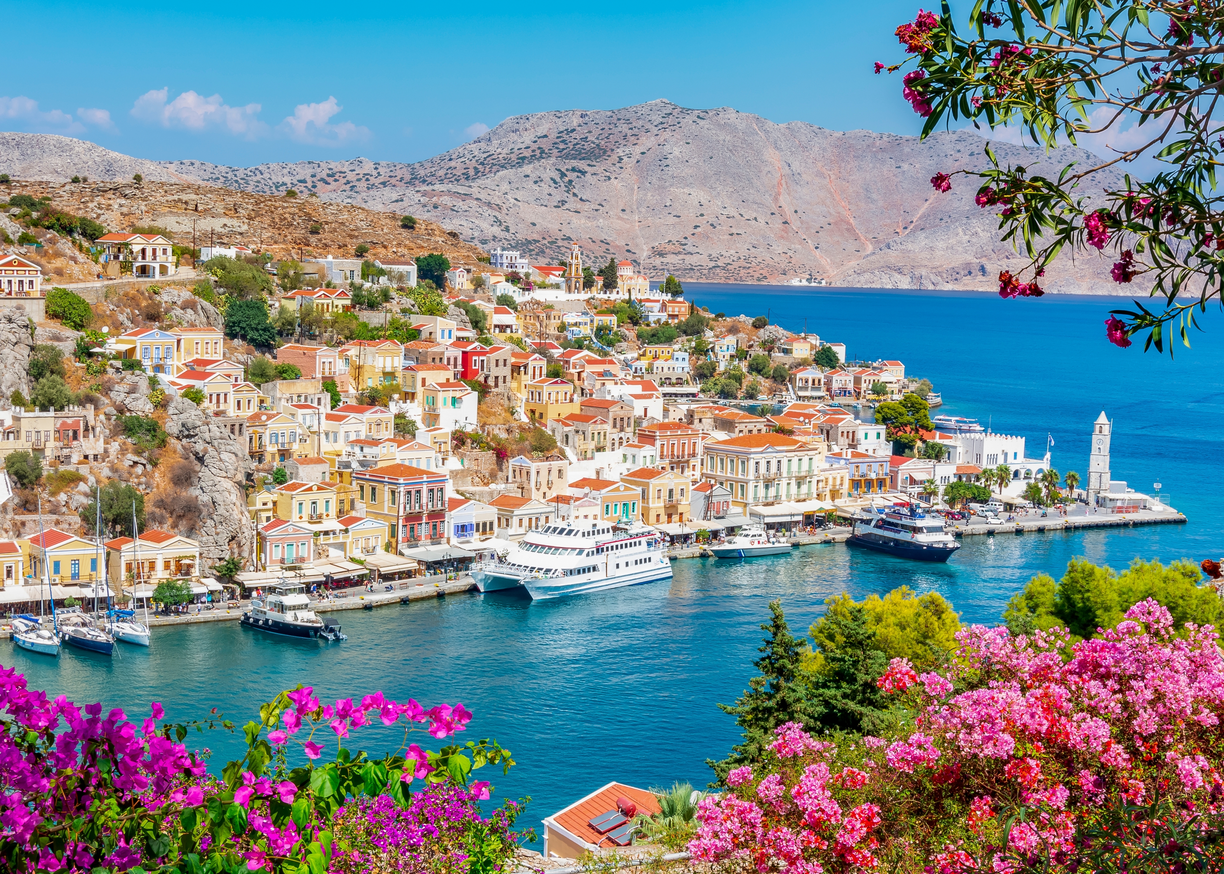 Farverige traditionelle huse og havn på Symi ø i Grækenland med blåt middelhav