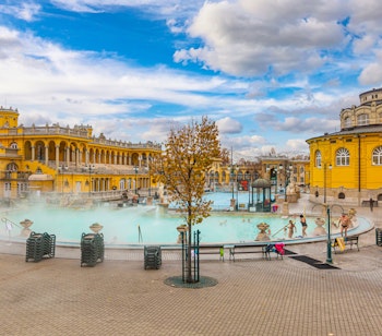 Det berømte Széchenyi termalbad i Budapest med sin karakteristiske gule neobarokke arkitektur og dampende udendørs bassiner, hvor besøgende nyder de helbredende termiske vande