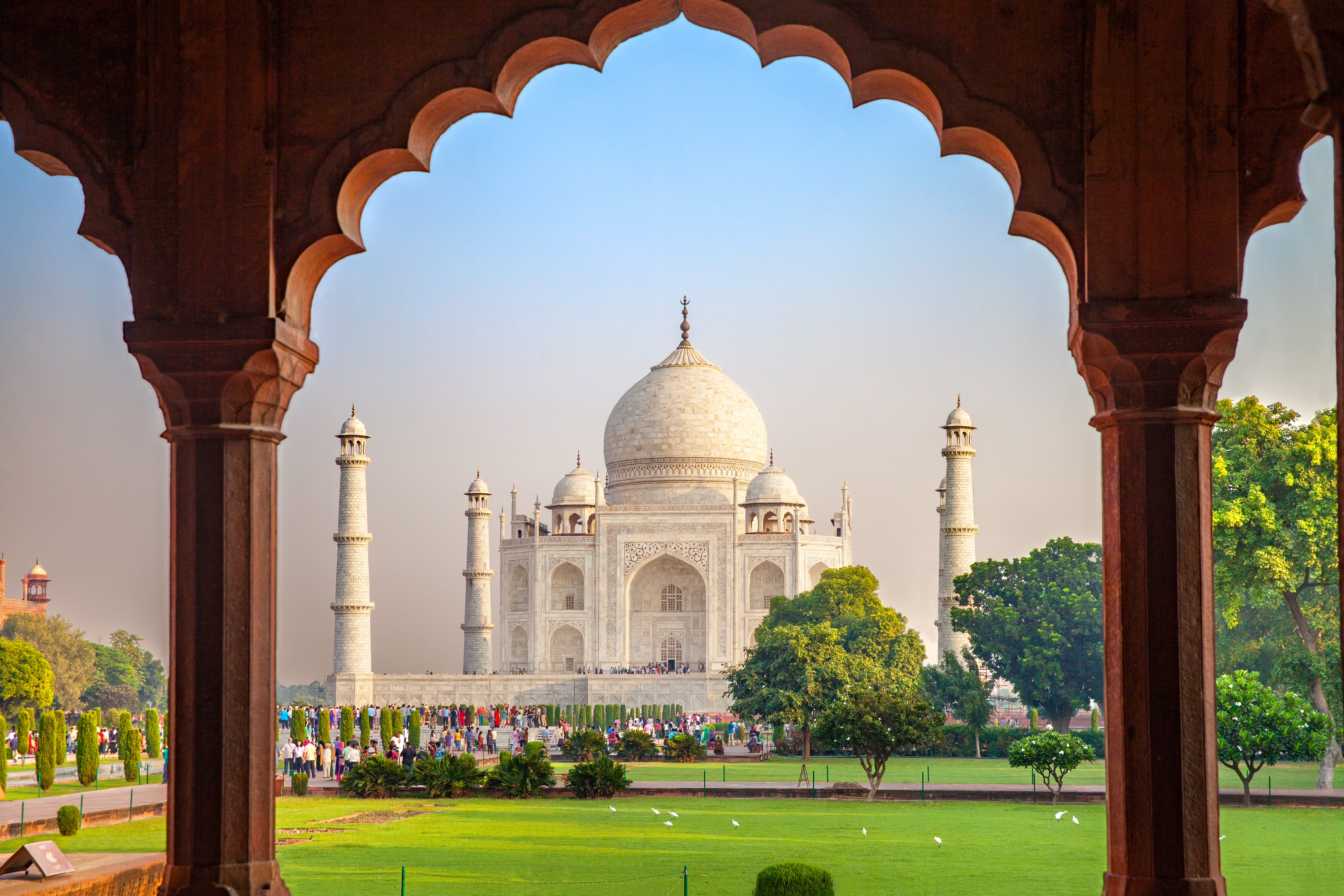 Taj Mahal set gennem traditionel mughal buegange i Agra Indien med turister og grønne haver
