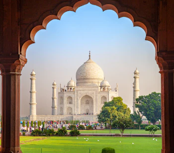 Taj Mahal set gennem traditionel mughal buegange i Agra Indien med turister og grønne haver