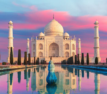 Taj Mahal i Agra ved solnedgang med smuk lyserød himmel og perfekt spejling i vandet, Indiens mest berømte marmormonument