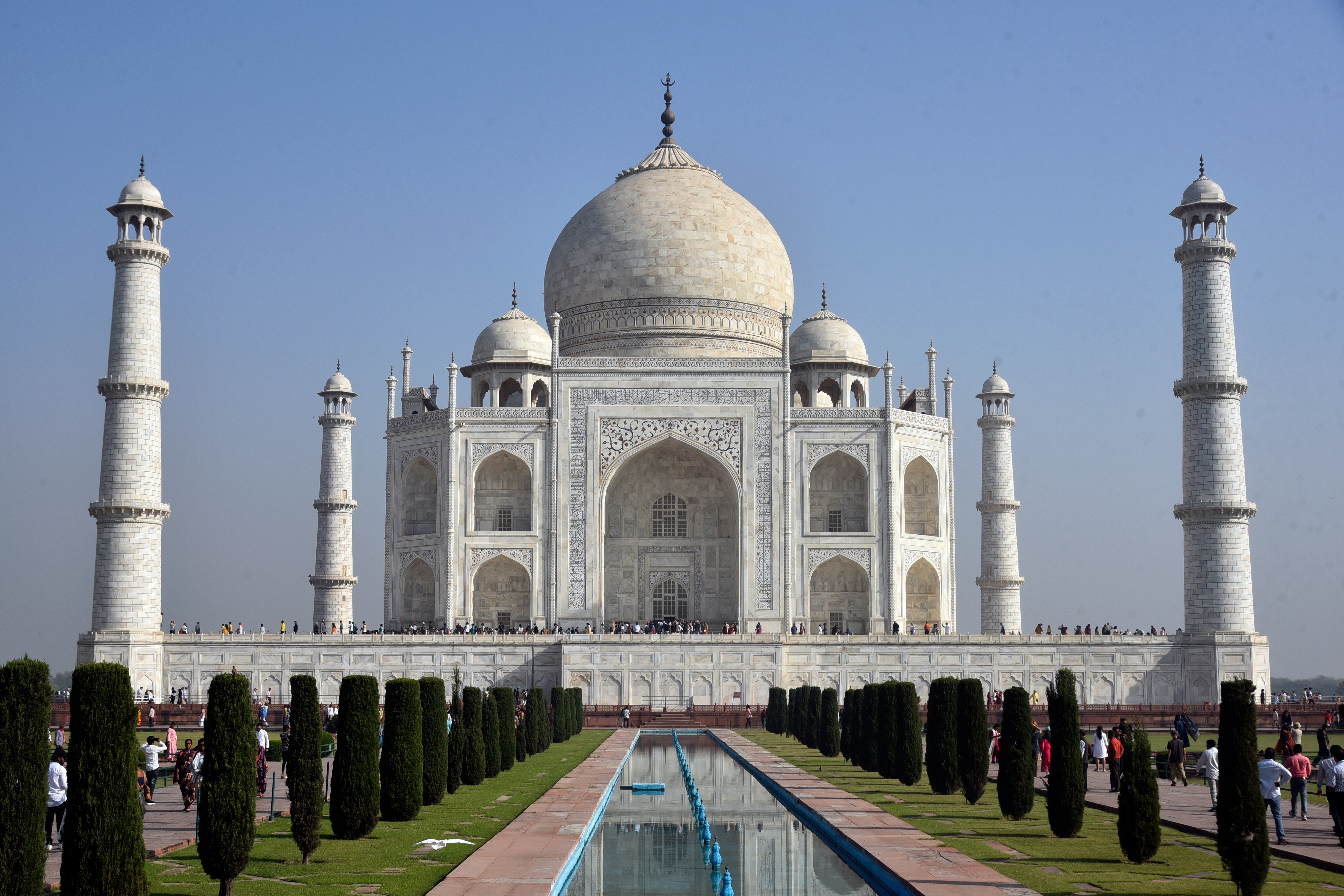 Det majestætiske Taj Mahal med hvide marmorkupler og minareter spejler sig i vandet ved solopgang i Agra, Indien