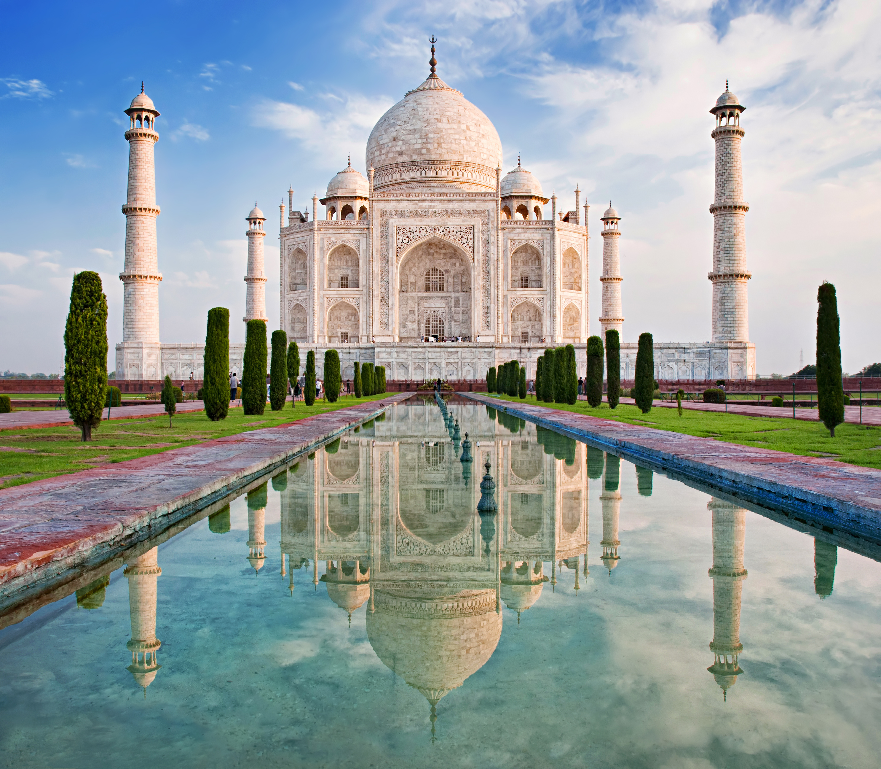 Det majestætiske Taj Mahal badet i gyldent morgenlys med perfekt spejling i vandbassinerne ved solopgang i Agra, Indien