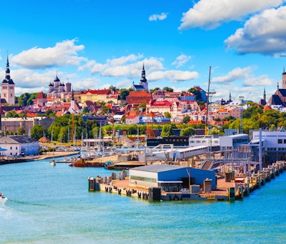 Betagende sommerudsigt over Tallinns historiske gamle bydel med farverige tage, middelalderlige tårne og den charmerende havn ved Østersøen