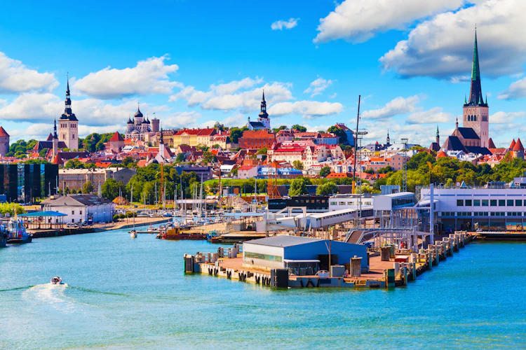 Panoramaudsigt over Tallinns historiske gamle bydel med middelalderarkitektur, kirketårne og havnefront i sommersolskin