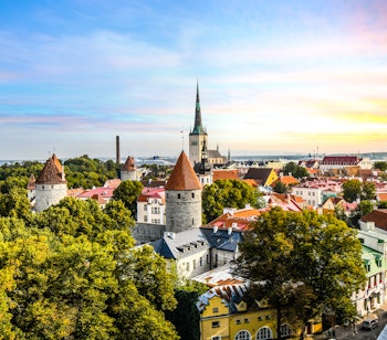 Betagende solnedgangsudsigt over Tallinns historiske middelalderby med farverige tage og gotiske spir set fra Toompea-højen i Estland