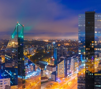 Panoramaudsigt over Tallinns moderne finansdistrikt med oplyste skyskrabere der spejler sig i aftenhimlen, Estlands hovedstad