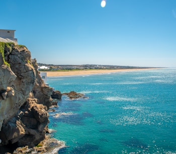 Betagende udsigt over kysten ved Tangier i Marokko med turkisblåt hav, gylden sandstrand og dramatiske klippeformationer
