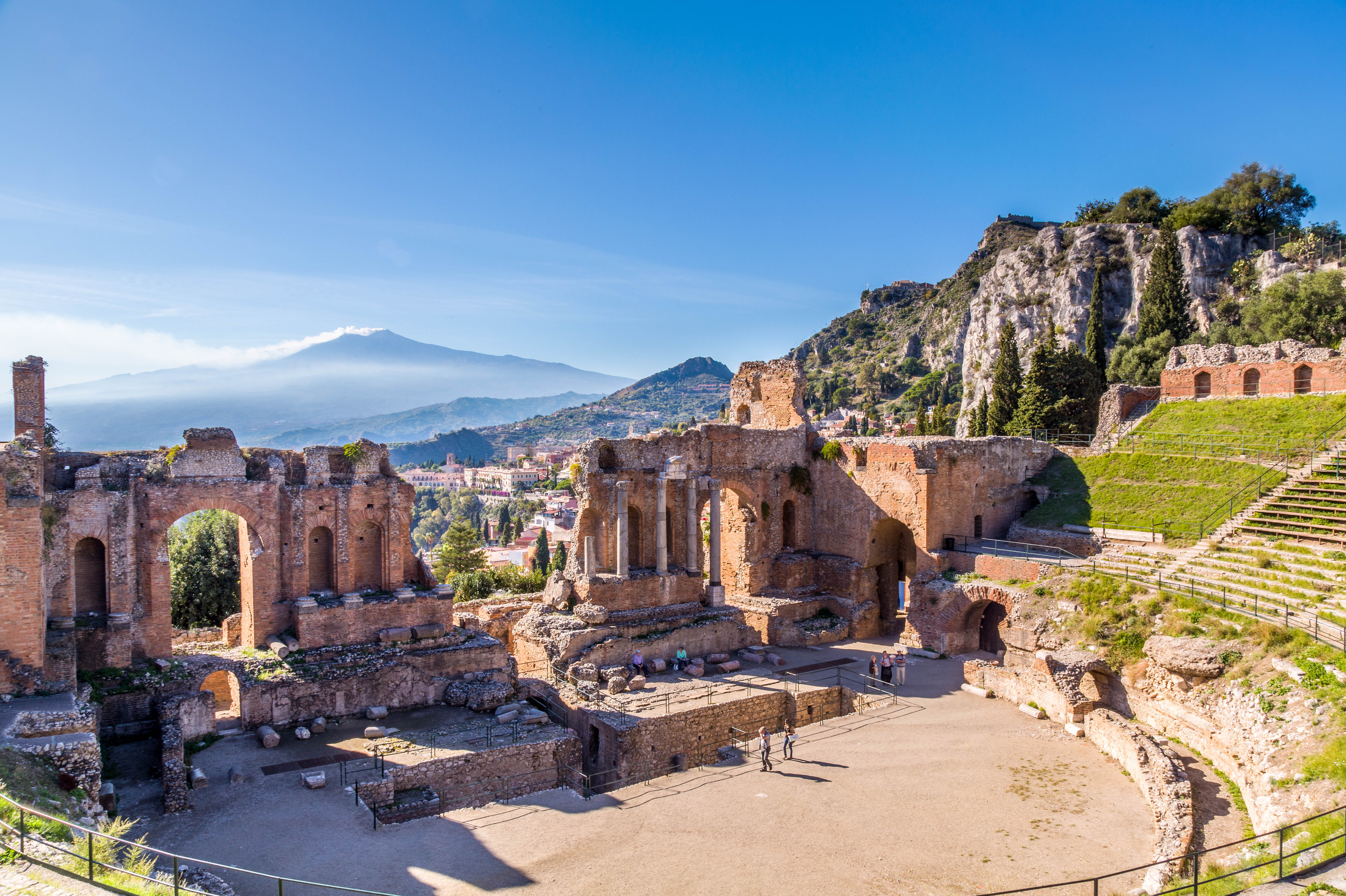 Det antikke græske teater i Taormina på Sicilien med den majestætiske Etna vulkan i baggrunden og azurblå himmel, der indrammer dette historiske kulturlandskab