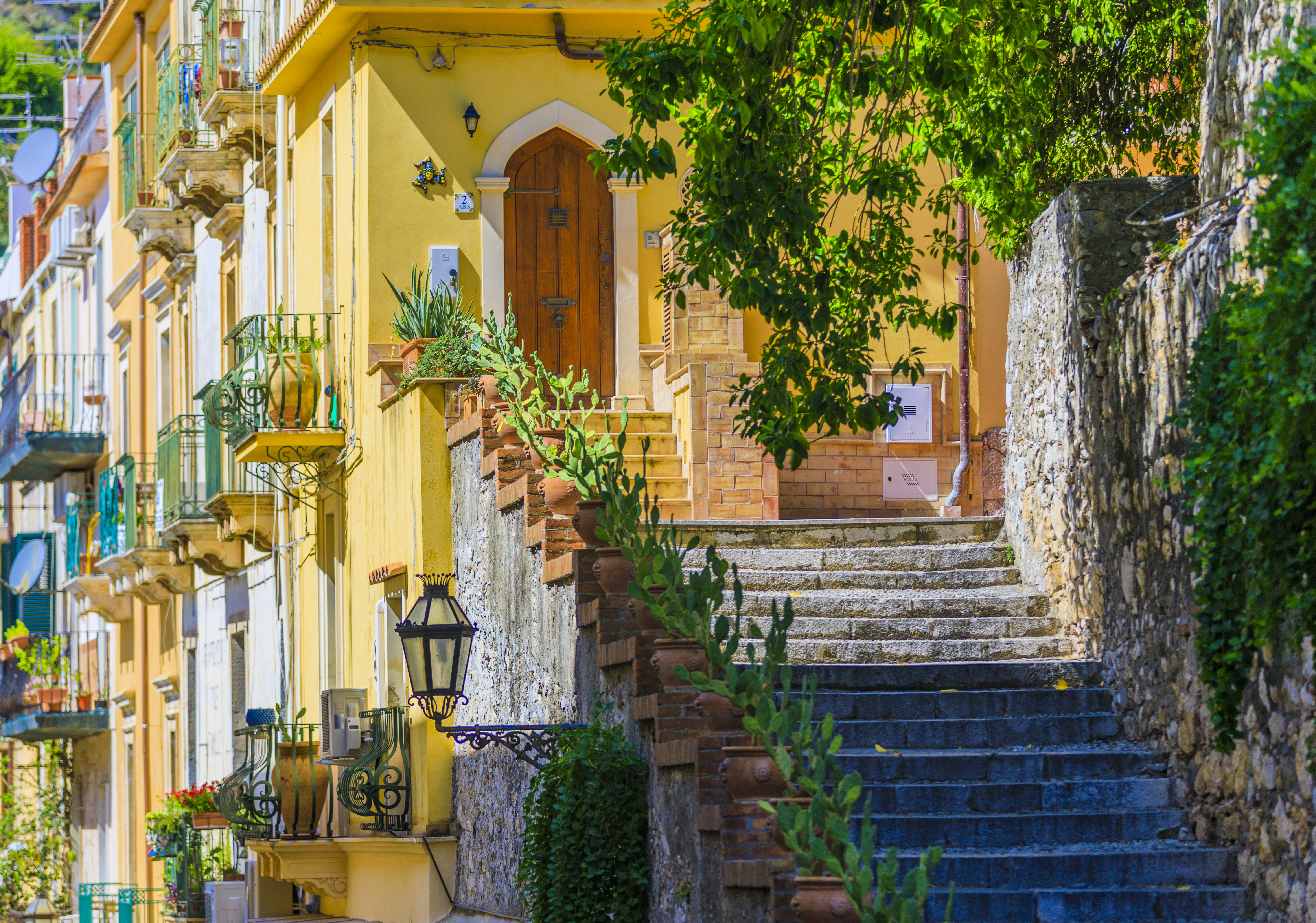Betagende udsigt over den maleriske by Taormina på Sicilien med dens farverige bygninger, charmerende gader og trapper, der snor sig ned mod det azurblå Middelhav og den dramatiske kystlinje