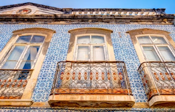 Historisk bylandskab i Tavira, Algarve med traditionelle hvide bygninger, romersk bro over Gilão-floden og kirketårne ved solnedgang