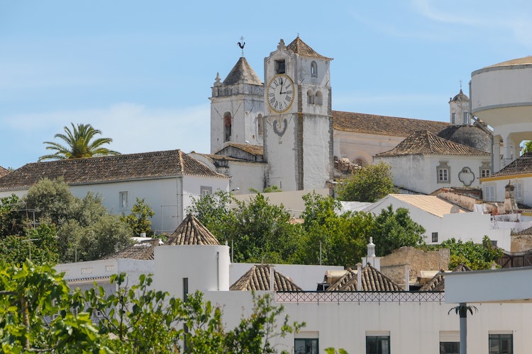 Udsigt over Taviras historiske bycentrum med klokketårnet fra Santa Maria do Castelo kirken i Algarve, Portugal under blå sommerhimmel