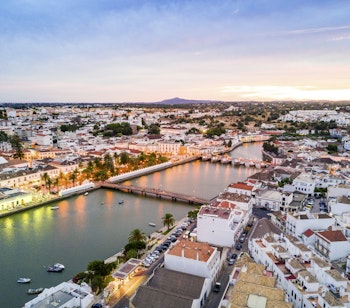 Panoramaudsigt over den historiske mauriske by Tavira med den romerske bro over Gilão-floden ved solnedgang i Algarve, Portugal