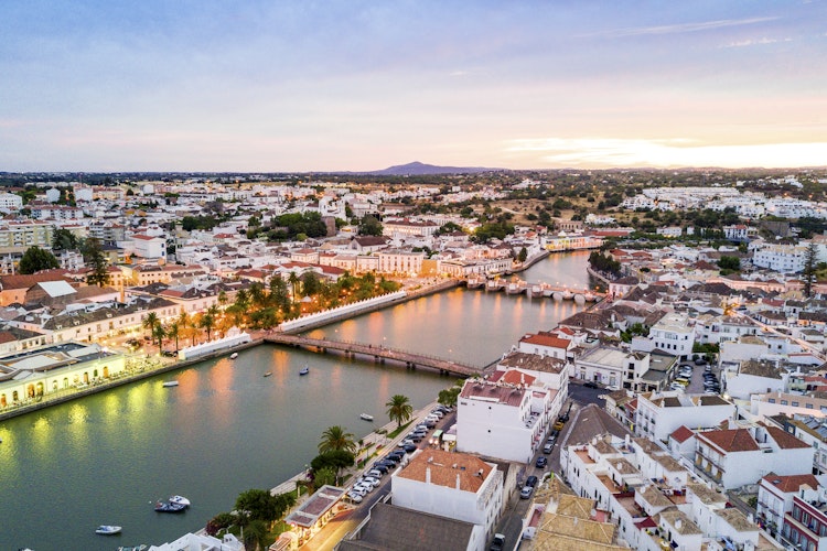 Panoramaudsigt over den historiske mauriske by Tavira med den romerske bro over Gilão-floden ved solnedgang i Algarve, Portugal